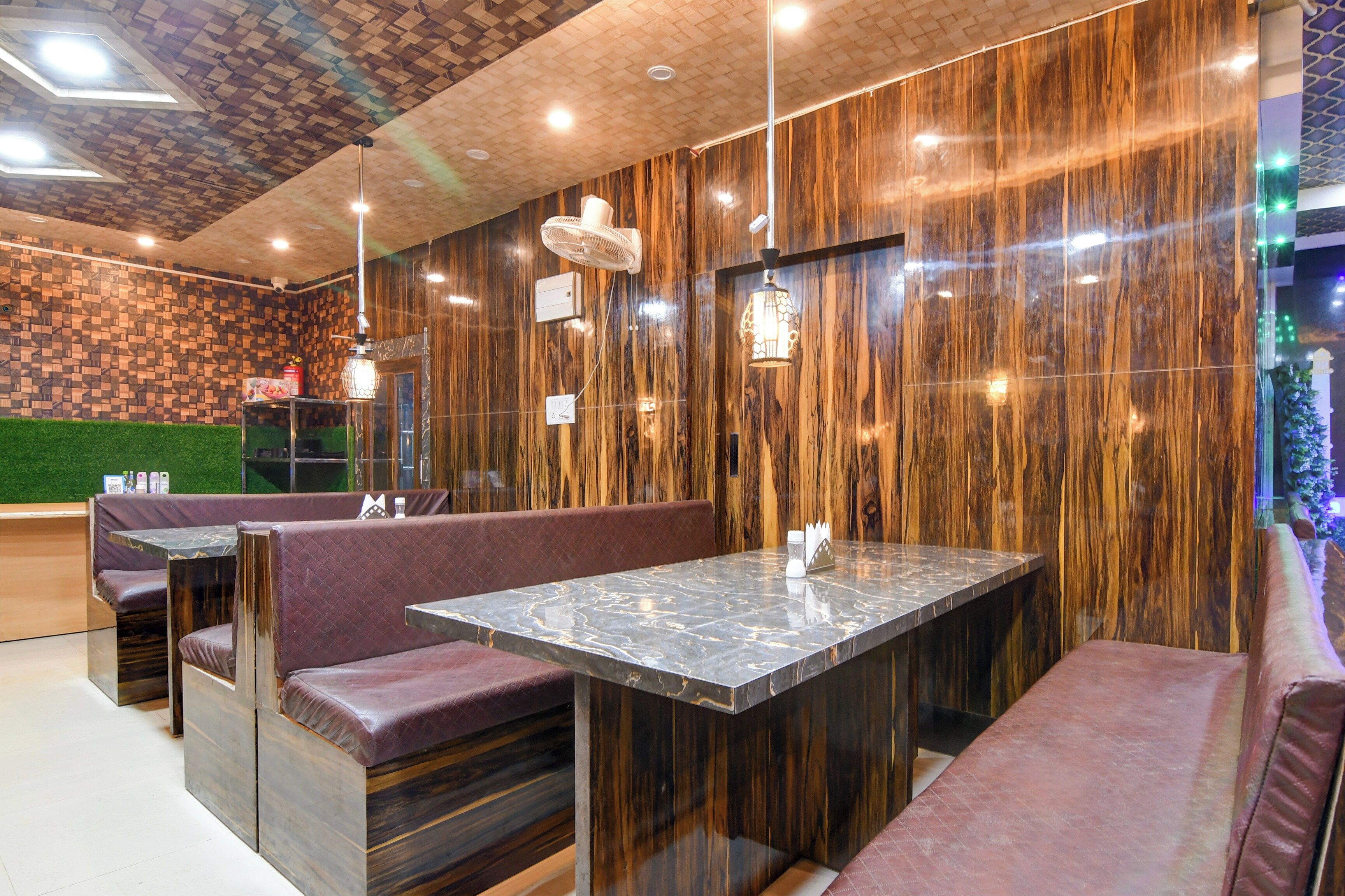 A restaurant interior with wooden panel walls, marble tables, and cushioned booths.