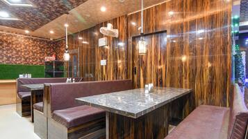 A restaurant interior with wooden panel walls, marble tables, and cushioned booths.