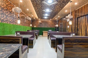 Ein Restaurantinneres mit Sitzecken, einer grünen Wand und einer Holzbalkendecke.