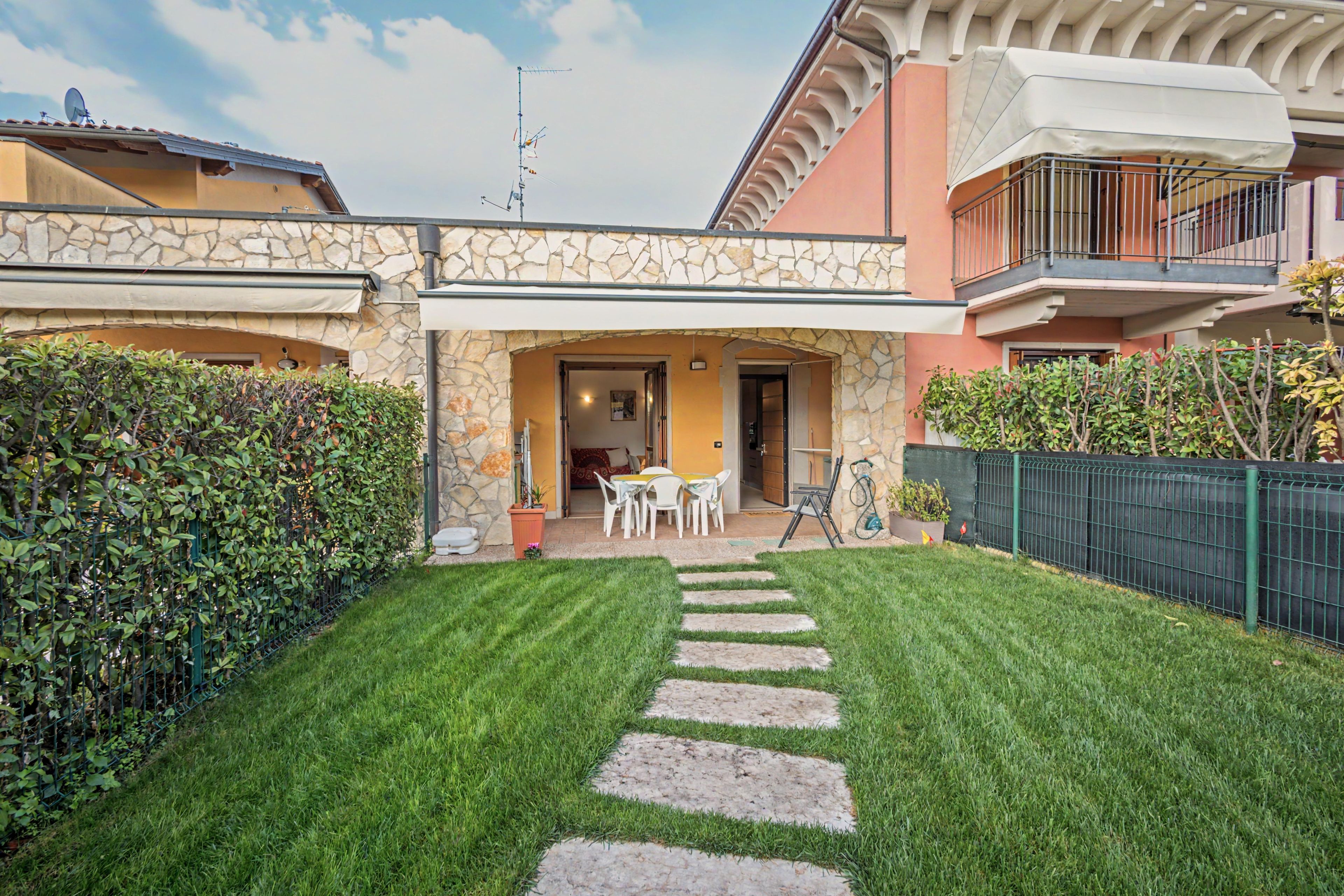 A courtyard with a stone pathway leading to a seating area with a table and chairs.