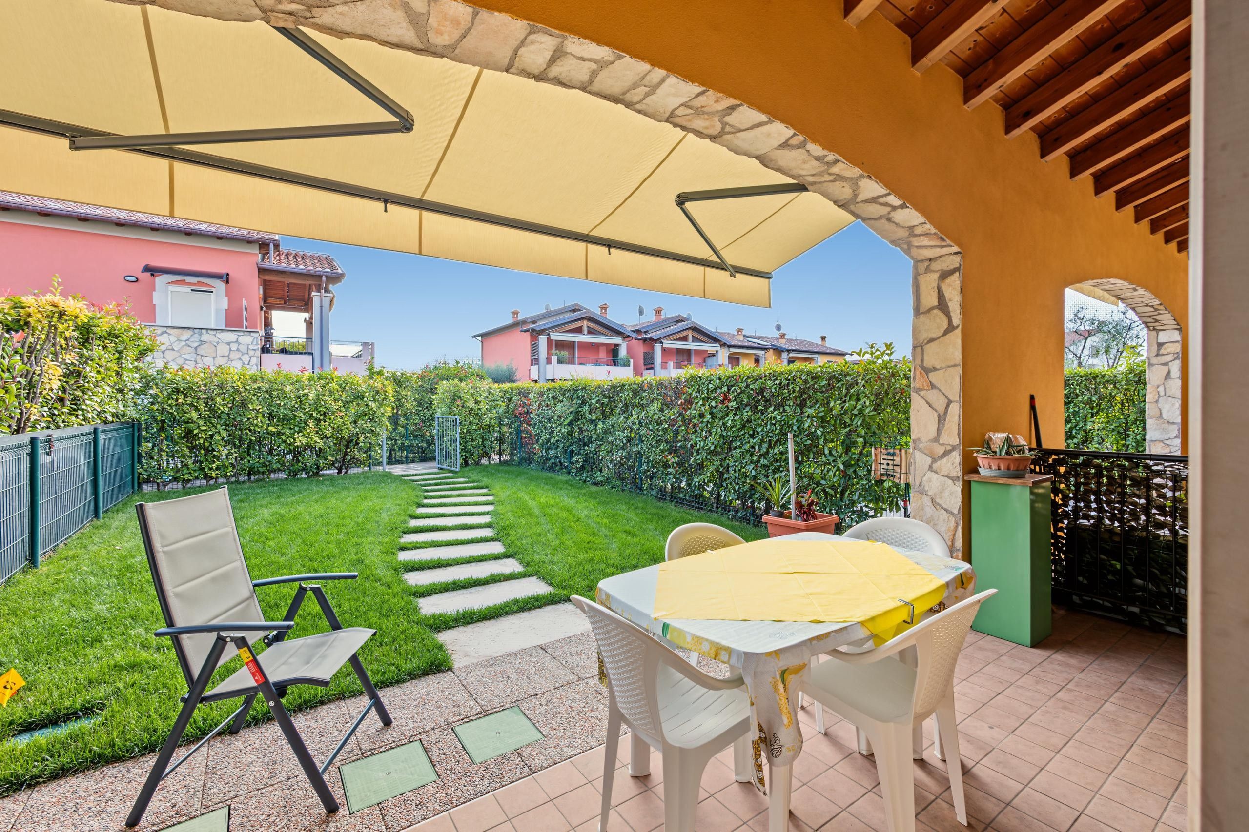 Une terrasse avec une table et des chaises, un espace salon abrité et une vue sur les maisons voisines.