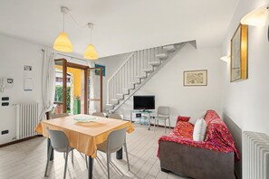 A modern living room with a dining area, a staircase, a TV, and a sofa. - Apartment 'Casa Vacanze Da Ricky App 6' with Shared Pool, Wi-Fi and Air Conditioning (Peschiera del Garda)