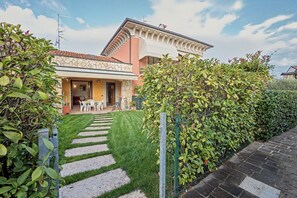 A two-story house with a stone facade, a paved garden with a stone pathway, and a fenced area with greenery. - Apartment 'Casa Vacanze Da Ricky App 6' with Shared Pool, Wi-Fi and Air Conditioning (Peschiera del Garda)