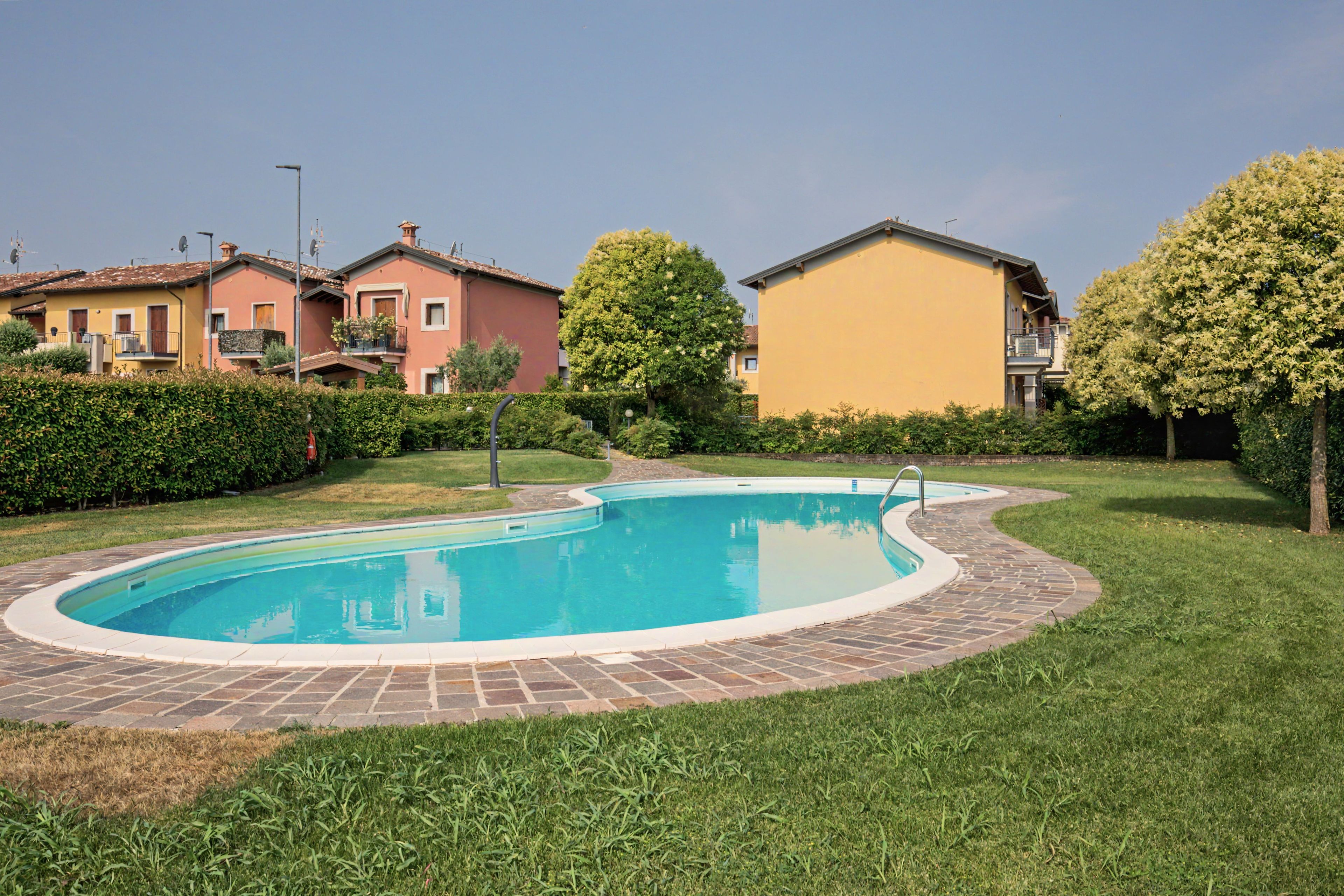 A residential area with a swimming pool, houses, and well-maintained lawns.