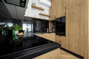 A modern kitchen with a black marble countertop, wooden cabinets, and a built-in oven. - Mrzezyno | Nadmorska 7F | Comfortable Apartment | Air conditioning | Parking (Mrzeżyno)