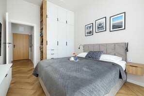 A bedroom with a bed, a nightstand, a wardrobe, and two framed pictures on the wall. - Mrzezyno | Nadmorska 7F | Comfortable Apartment | Air conditioning | Parking (Mrzeżyno)