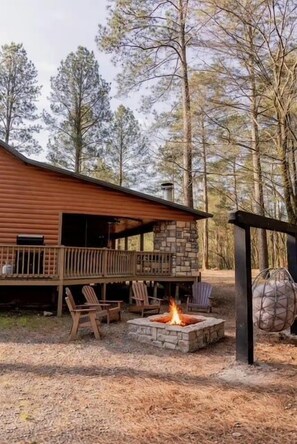 A cabin with a deck, outdoor seating, and a fire pit. - Game Console-Horseshoe Pit-Swing Chairs-Hot Tub-Hearthstone (Broken Bow)
