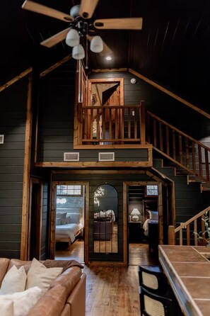A multi-level cabin with a loft bedroom, a dining area, and a staircase. - Game Console-Horseshoe Pit-Swing Chairs-Hot Tub-Hearthstone (Broken Bow)