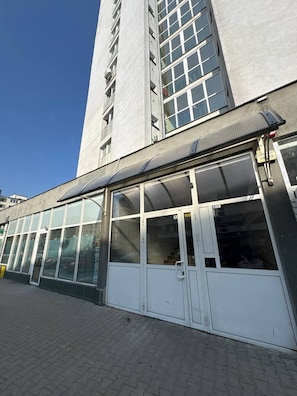 Ein Gebäude mit einer großen Glasfassade, einem flachen Dach und einer Tür mit einem Metallgriff.
