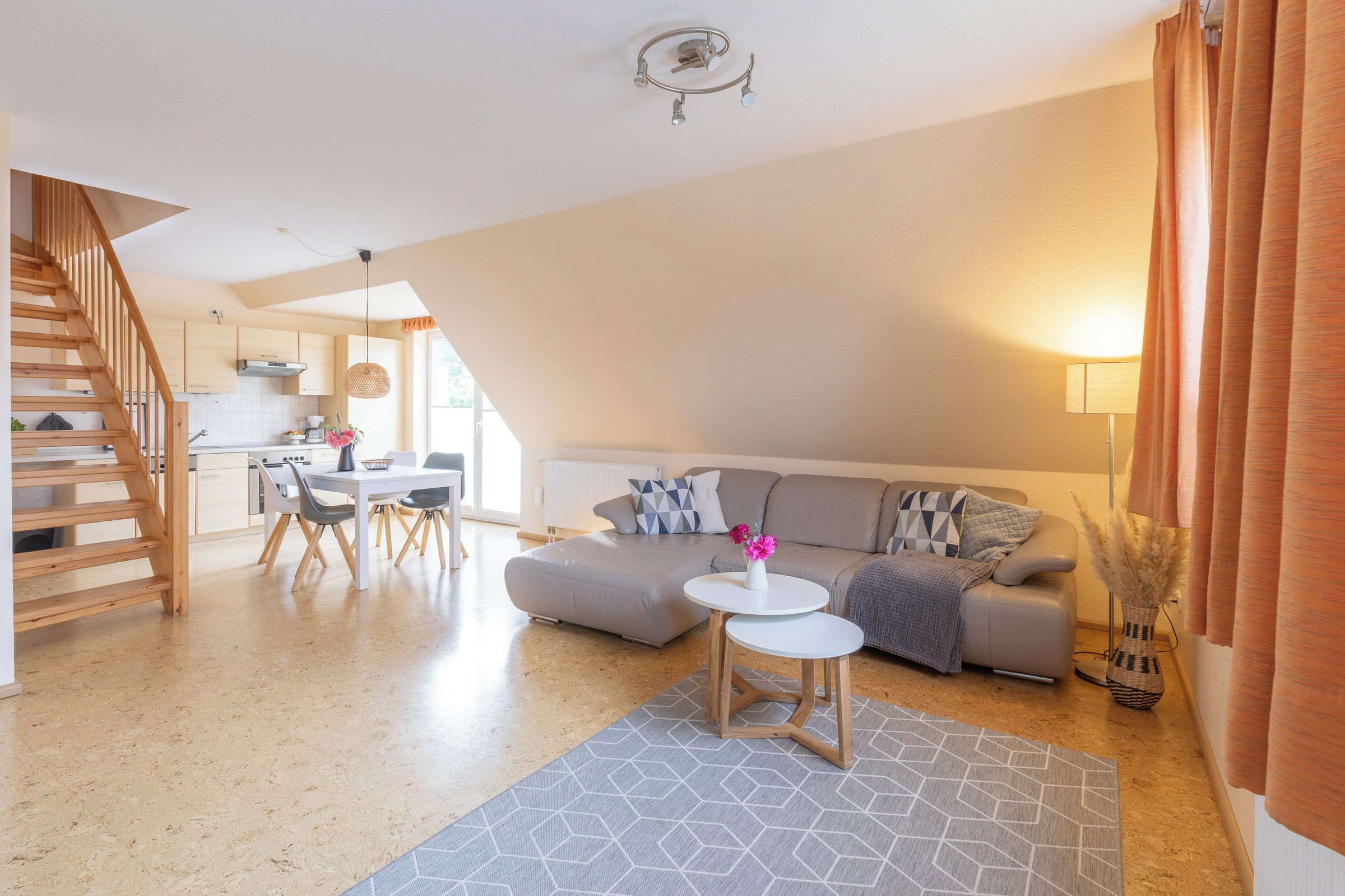 Ein zeitgemäßer Wohnraum mit Treppe, Essbereich, Sofa und Küche.