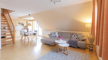 Ein zeitgemäßer Wohnraum mit Treppe, Essbereich, Sofa und Küche.