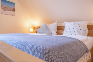 Un lit bien fait, avec une couverture à motifs, des oreillers et une petite lampe de chevet.
