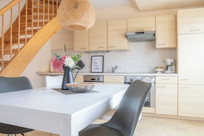 Une cuisine moderne avec des meubles en bois, une table à manger avec des chaises et un escalier avec des rampes en bois.