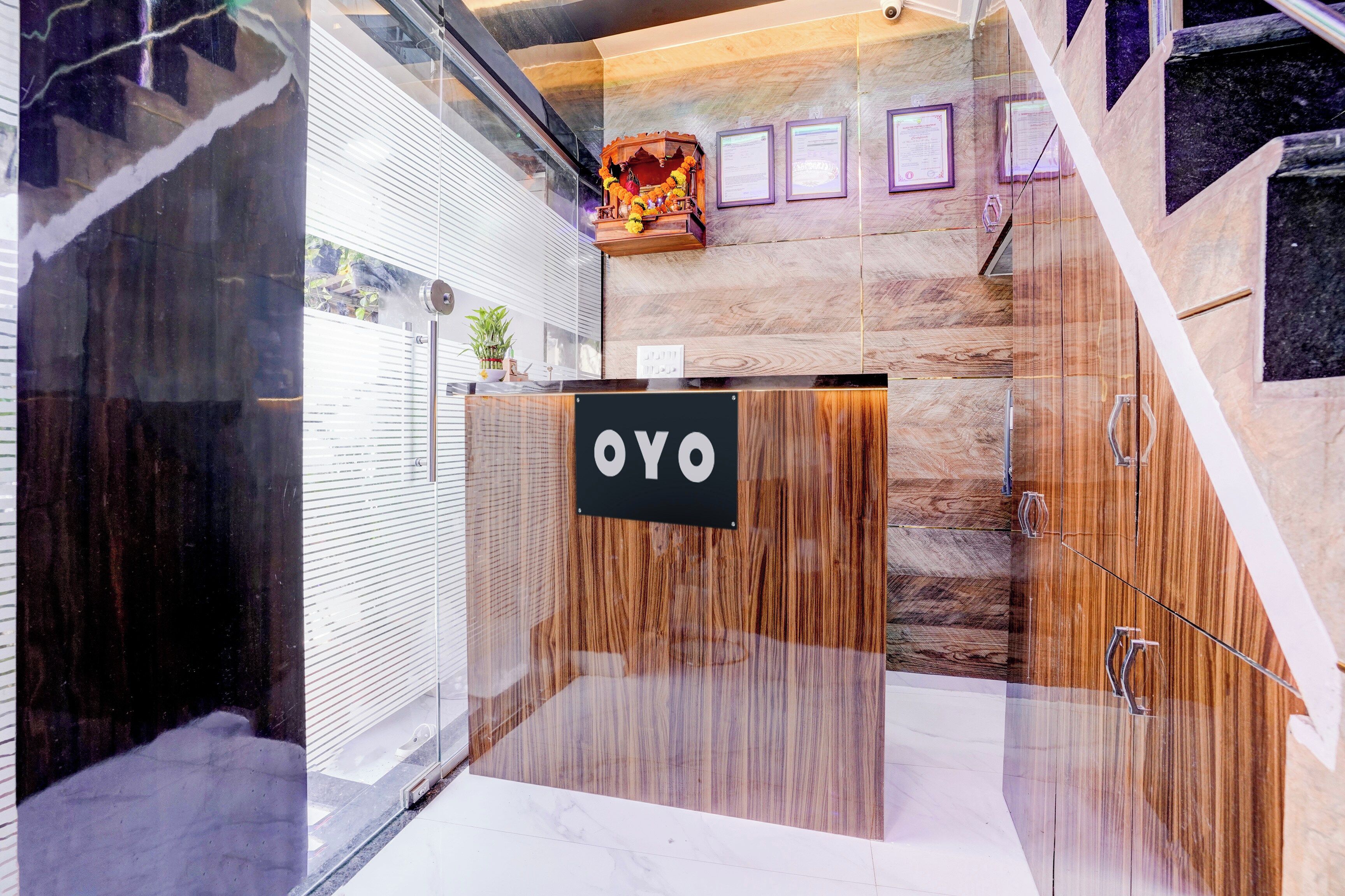 A reception desk with a sign reading 'OYO' and a staircase leading to an upper level.