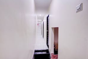 A corridor with a black and white tiled floor, white walls, and a door at the end. - Hotel O Class Inn (Mumbai)