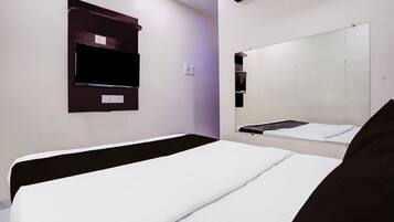 A hotel room with a bed, a TV mounted on the wall, and a mirror.
