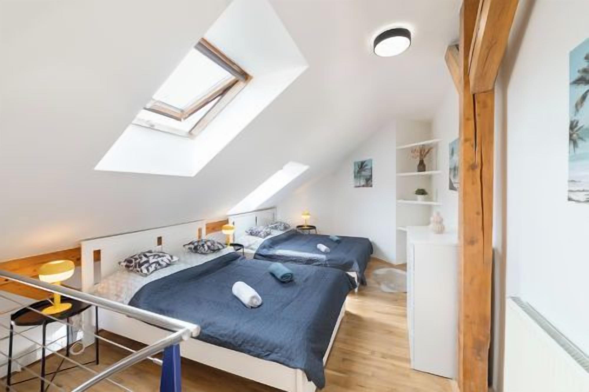 Ein Schlafzimmer mit zwei Betten, einem Oberlicht, Holzboden und einem weißen Kleiderschrank.