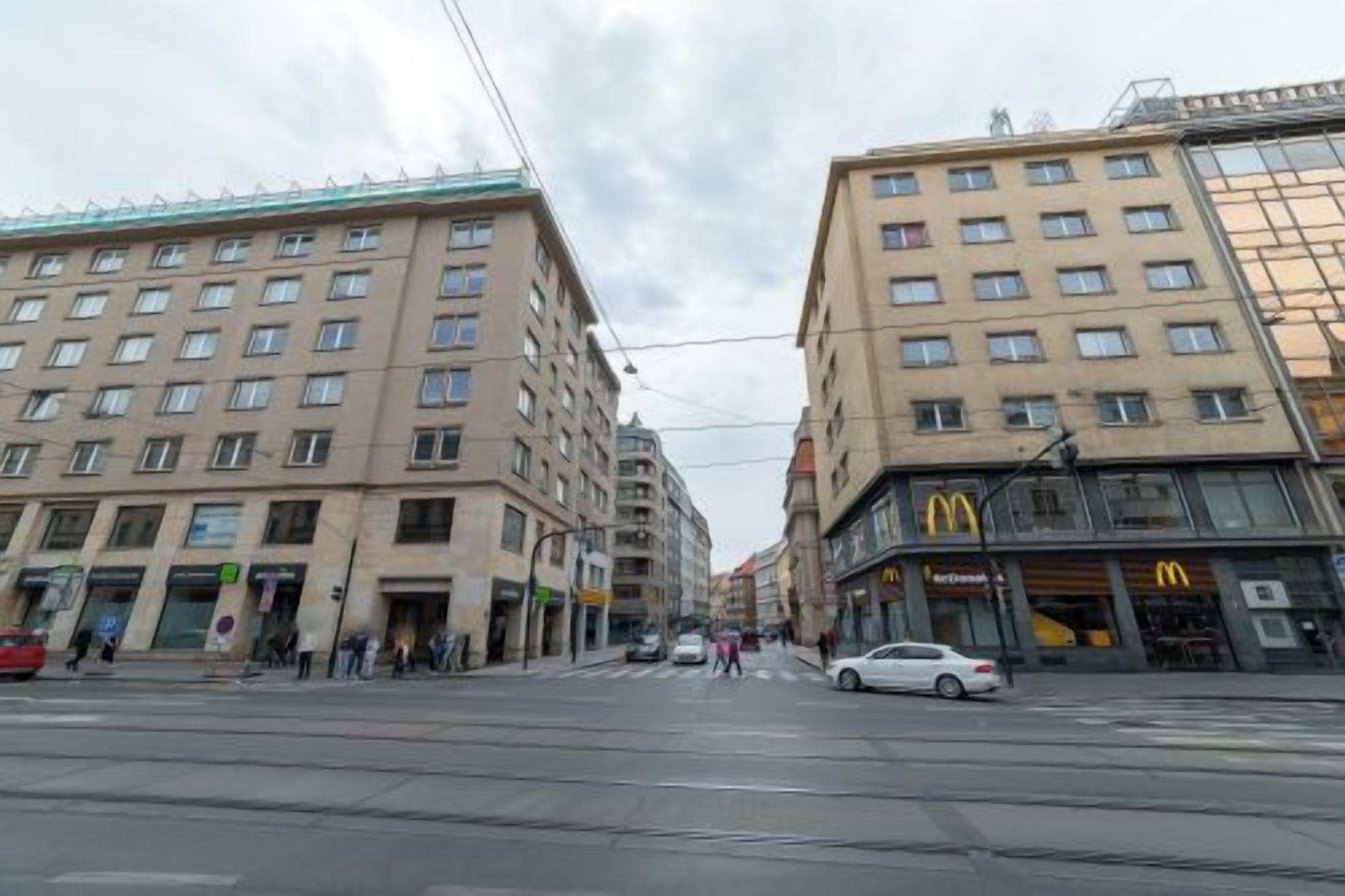 Straßenansicht mit Gebäuden, einem McDonald's Restaurant und einer Straßenbahnlinie.