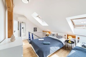 Ein Schlafzimmer mit Dachfenster, einem Bett, Nachttischen und einem Schreibtisch.