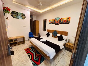A bedroom with a bed, bedside tables, a chair, a rug, and artwork on the walls. - Raj Rani Complex And Hotel Restaurant (Mainpuri)