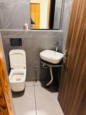 A compact bathroom with a toilet, sink, and a mirror. - Raj Rani Complex And Hotel Restaurant (Mainpuri)