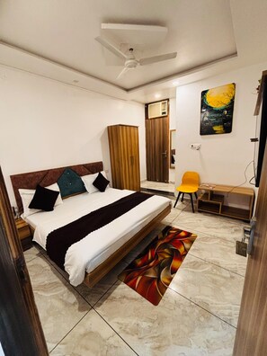 A bedroom with a bed, a desk, a chair, a wardrobe, and a ceiling fan. - Raj Rani Complex And Hotel Restaurant (Mainpuri)