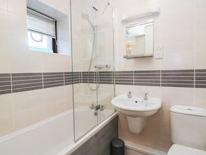 A bathroom with a glass-enclosed shower, a white sink, and a toilet. - Rooftops (Grange-over-Sands)