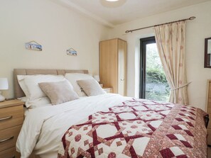 A bedroom with a bed, bedside tables, a wardrobe, and a window with curtains. - Rooftops (Grange-over-Sands)
