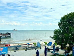 Ein Ufergebiet mit einer Mole, einem Strand und einer Reihe von Sitzgelegenheiten im Freien mit Sonnenschirmen.