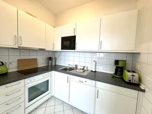 A compact kitchen with white cabinets, a microwave, a toaster, and a kettle. - House With sea View - Apt. 2 (Wyk auf Foehr)