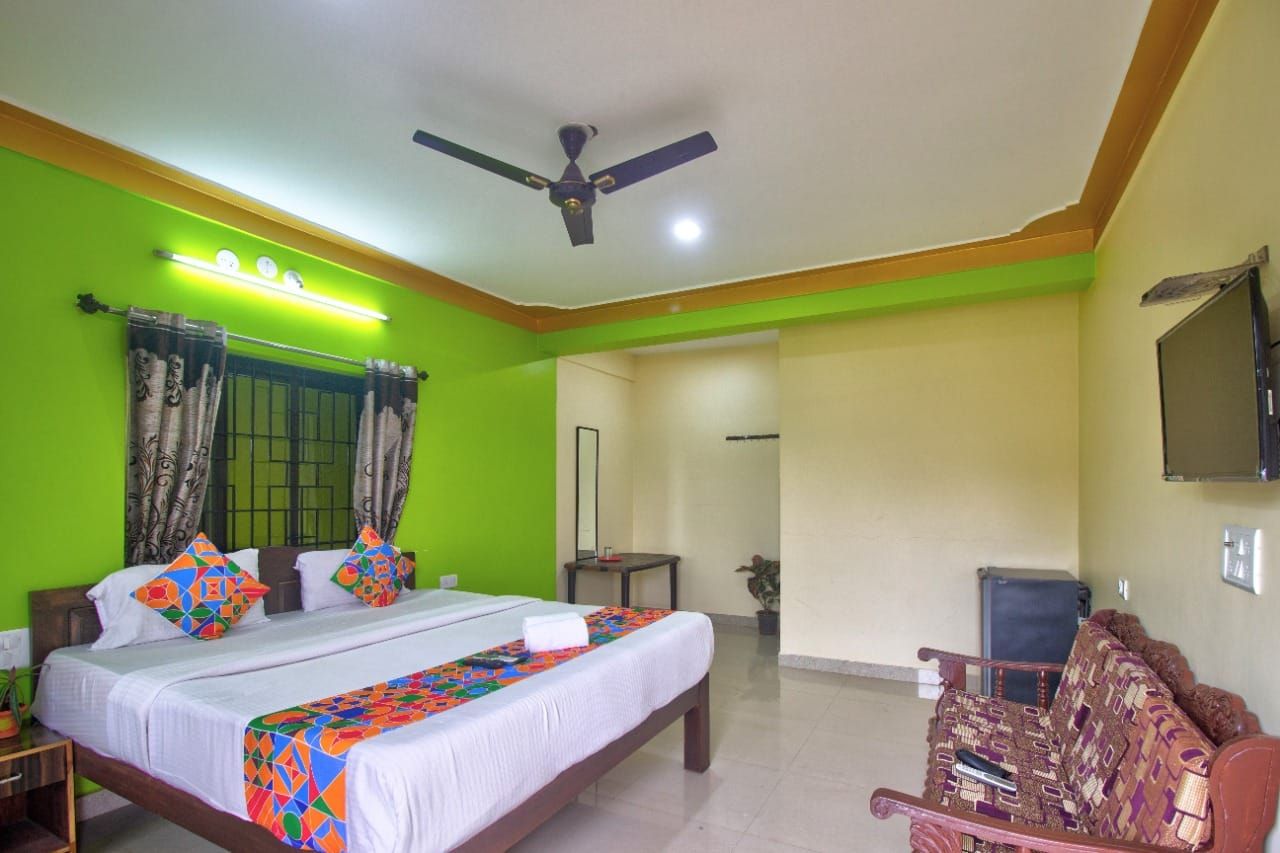 A hotel room with a bed, a ceiling fan, a television, and a sofa.