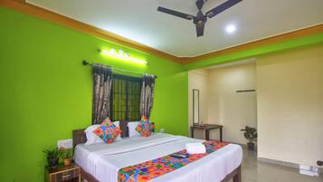 A hotel room with a bed, bedside table, and a ceiling fan.