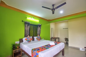 A hotel room with a bed, bedside table, and a ceiling fan. - The Baga Beach 24in (Calangute)