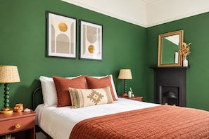 A bedroom with a bed, two bedside tables, a nightstand, a mirror, and a fireplace. - Modern 2BR Apartment near Leith Walk (Edinburgh)