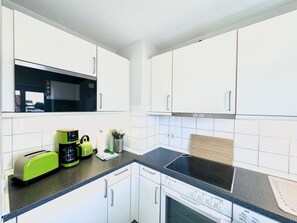 Una cocina moderna con armarios blancos, un microondas negro, un tostador verde y una estufa.