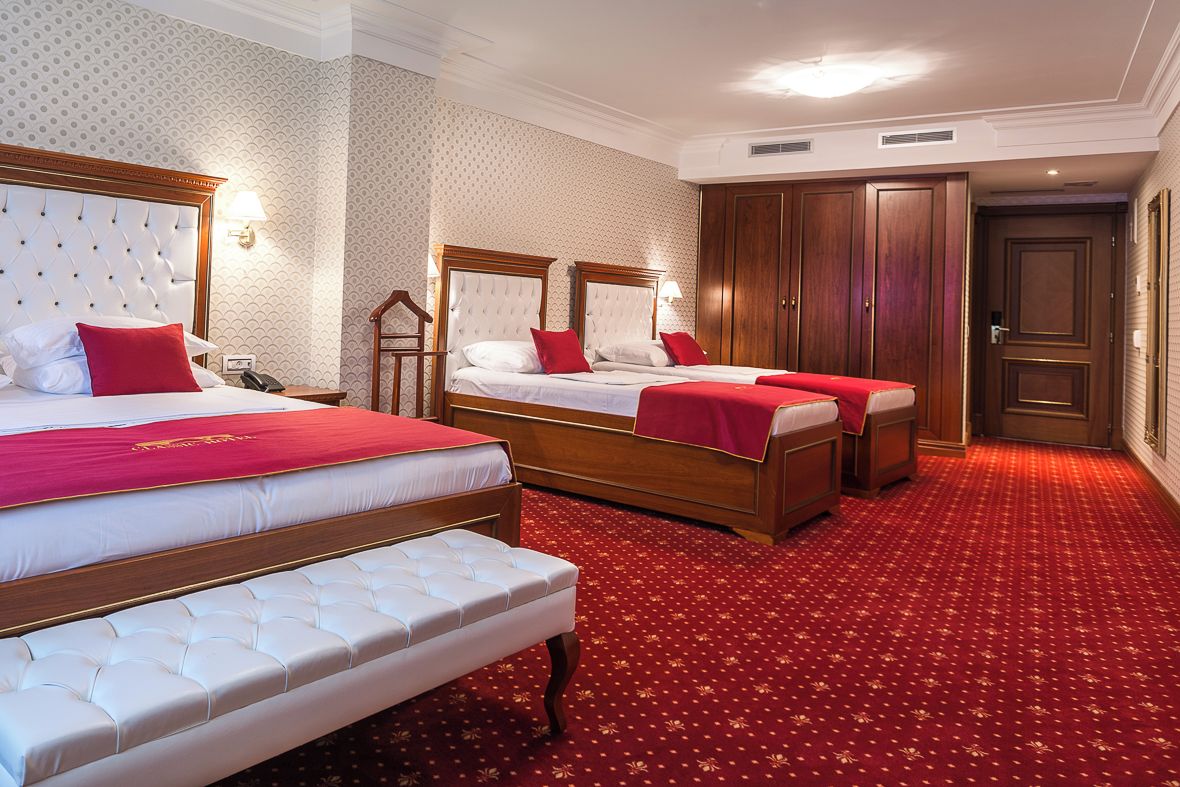 Una habitación de hotel con dos camas, alfombra roja y armarios de madera.