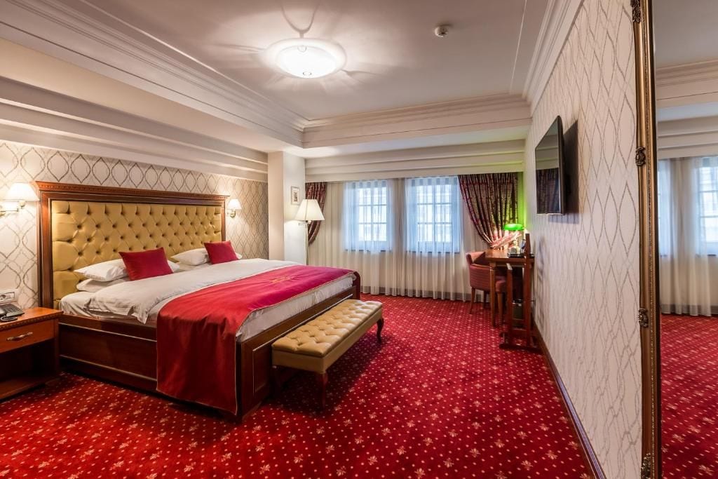 A hotel room with a large bed, a desk, and a television.