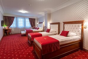 Ein Hotelzimmer mit drei Betten, einem roten Teppich und einer Wand mit Muster.