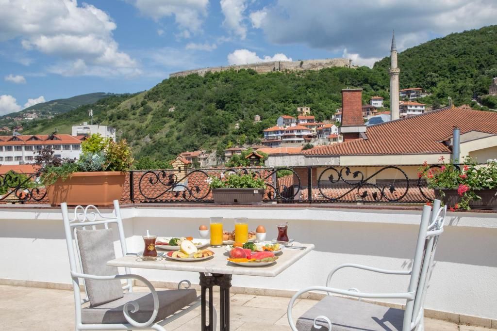 Una terraza con una mesa preparada para el desayuno, con vista a un pueblo con una colina y un minarete.