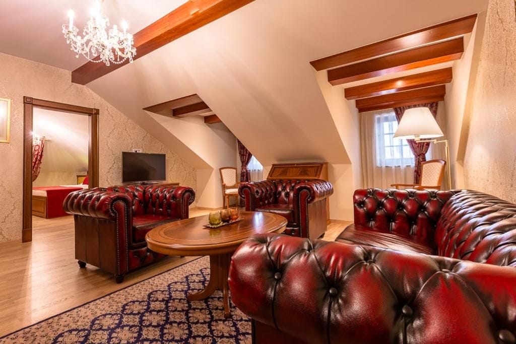 Amplia sala de estar con sofás de cuero, una mesa de centro de madera y un candelabro.