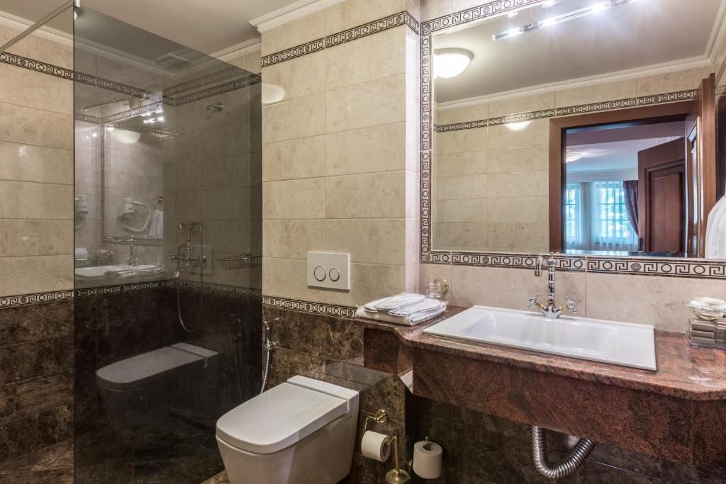 Un baño con ducha de vidrio, lavamanos e inodoro.