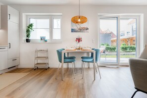 Eine moderne Küche mit Essbereich, ein Tisch für zwei Personen gedeckt, ein Blumentopf und Blick ins Freie.