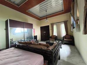 A hotel room with a bed, a sofa, a dining table, and a large mirror. - Cozzy Aishaf Hills (bogor)