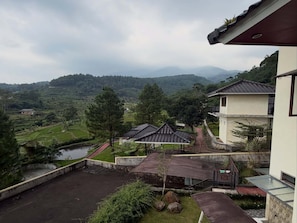 Un quartier résidentiel avec des bâtiments de style traditionnel, un petit étang et une vue sur des collines lointaines.
