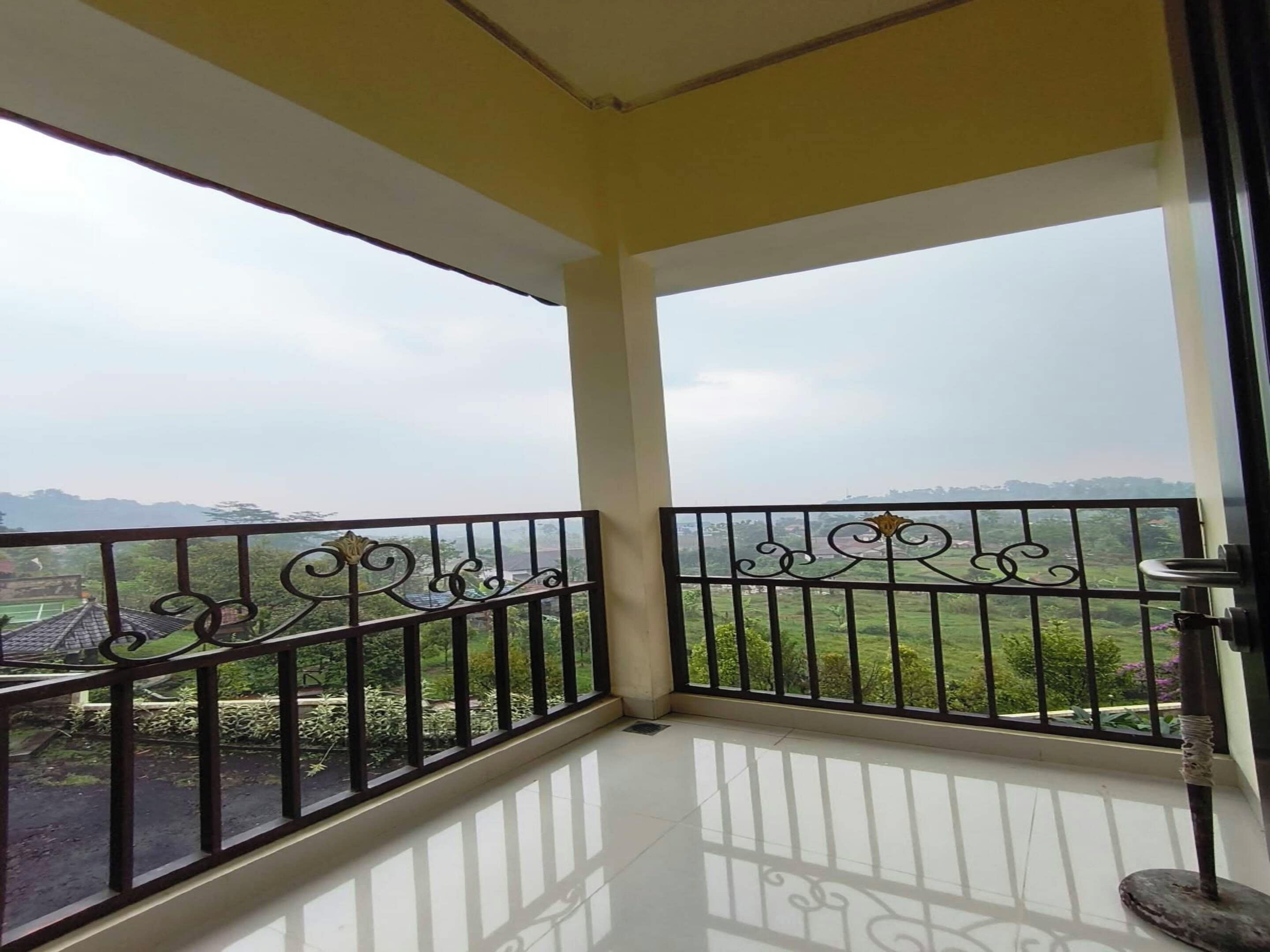 A balcony with a view of a green landscape and distant buildings.