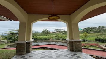A covered outdoor area with a checkered floor, stone pillars, and a view of a green landscape.