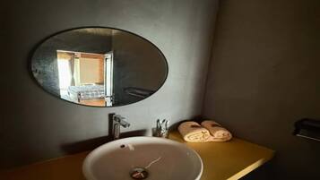 Een badkamer met een ronde spiegel, een wastafel en een handdoekhouder.