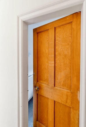 A wooden door with a brass doorknob, white trim, and a visible radiator behind it. - Room-bed n Breakfast Direct From Airport (Edinburgh)