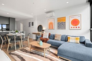 A modern living room with a dining area, a sofa, and a coffee table. - City View 2 Bedroom with Pool (Melbourne)