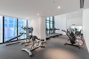 A gym with treadmills, weight machines, and exercise bikes, large windows, and a clean, modern design. - City View 2 Bedroom with Pool (Melbourne)